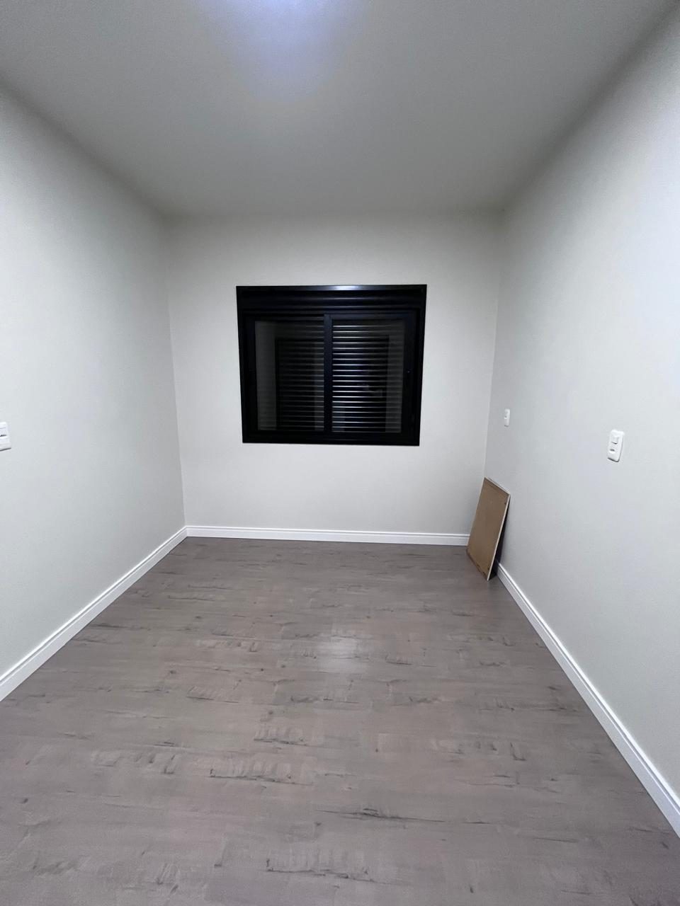 Quarto com piso laminado e janela com persiana